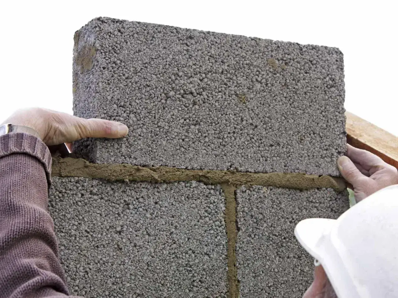 Pose d'un parpaing pour un mur. La hauteur maxi mur parpaing de 10 est respect&eacute;e. Mains de ma&ccedil;on au travail.