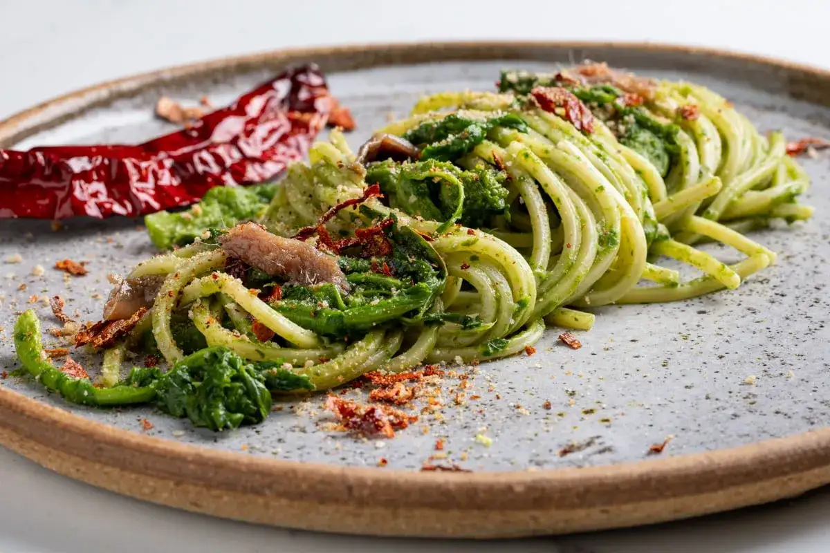 Un gustoso piatto tipico Basilicata: spaghetti verdi con verdure, acciughe e peperoncino secco.