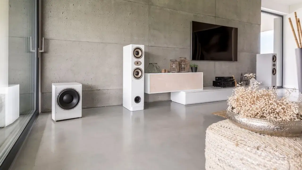 Salon moderne avec mur en **enduit sur b&eacute;ton int&eacute;rieur**, syst&egrave;me audio blanc, TV et mobilier &eacute;pur&eacute;.