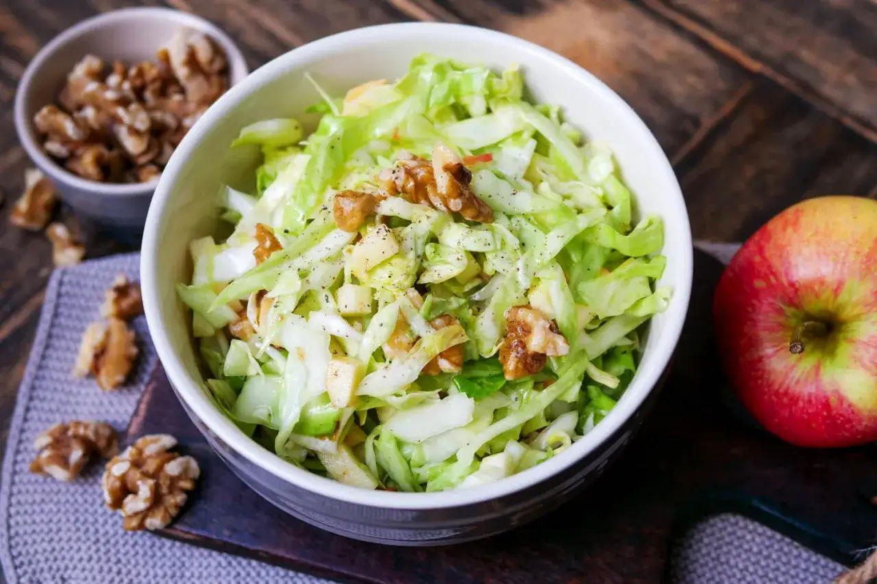 Frischer Spitzkohl Salat mit knackigen Waln&uuml;ssen und Apfelst&uuml;cken, garniert mit Pfeffer.