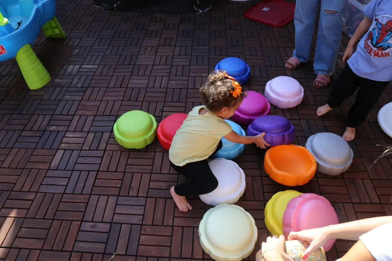 Ein kleines Mädchen spielt mit bunten Stapelsteinen. Viele kreative Stapelsteine Ideen sind hier zu sehen, wie sie die Kinder zum Bauen und Spielen anregen.