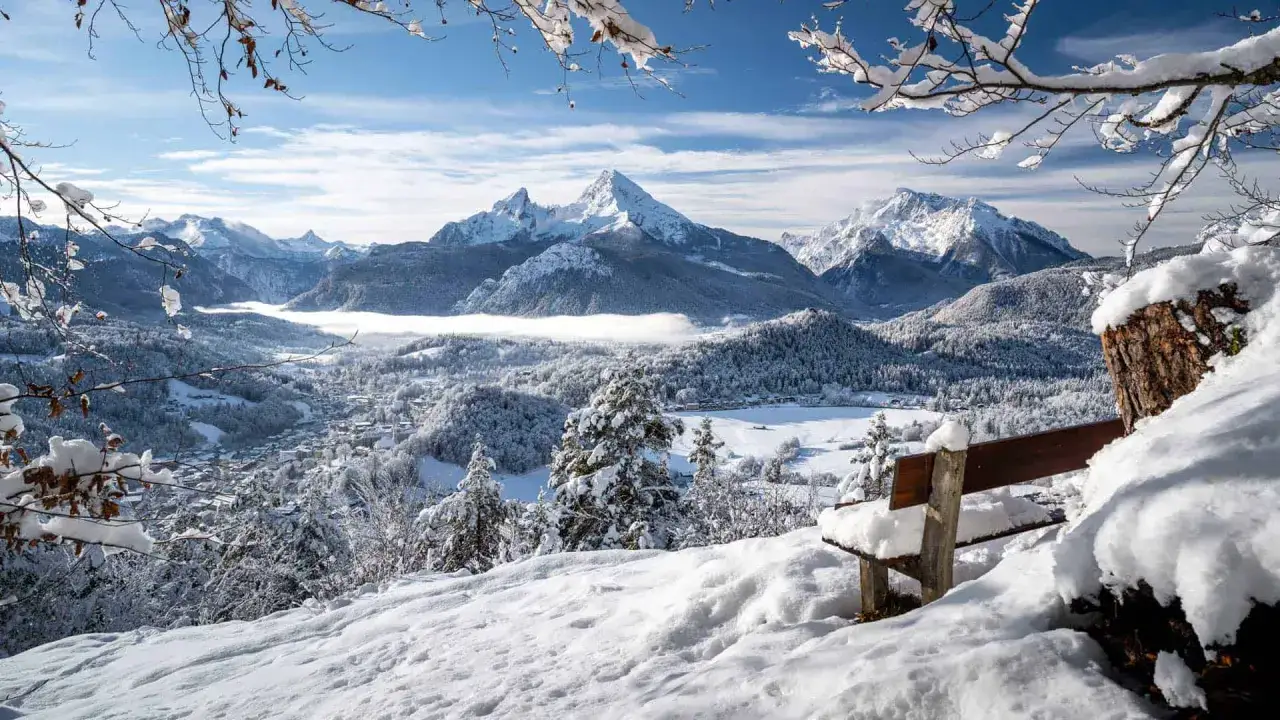 Schneebedeckte Berge und ein verschneites Tal mit einem Dorf. Perfekte reiseziele winter für Ruhe und Natur.