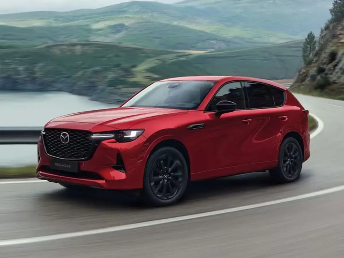 Czerwona Mazda CX-60 3.3 diesel na krętej drodze wśród zielonych wzgórz.