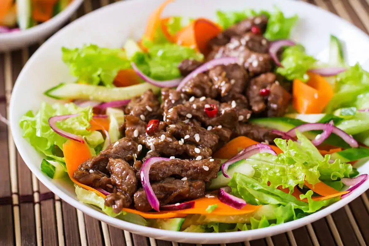 Salade de viandes froides savoureuse avec des lanières de bœuf, des légumes croquants et des oignons rouges.