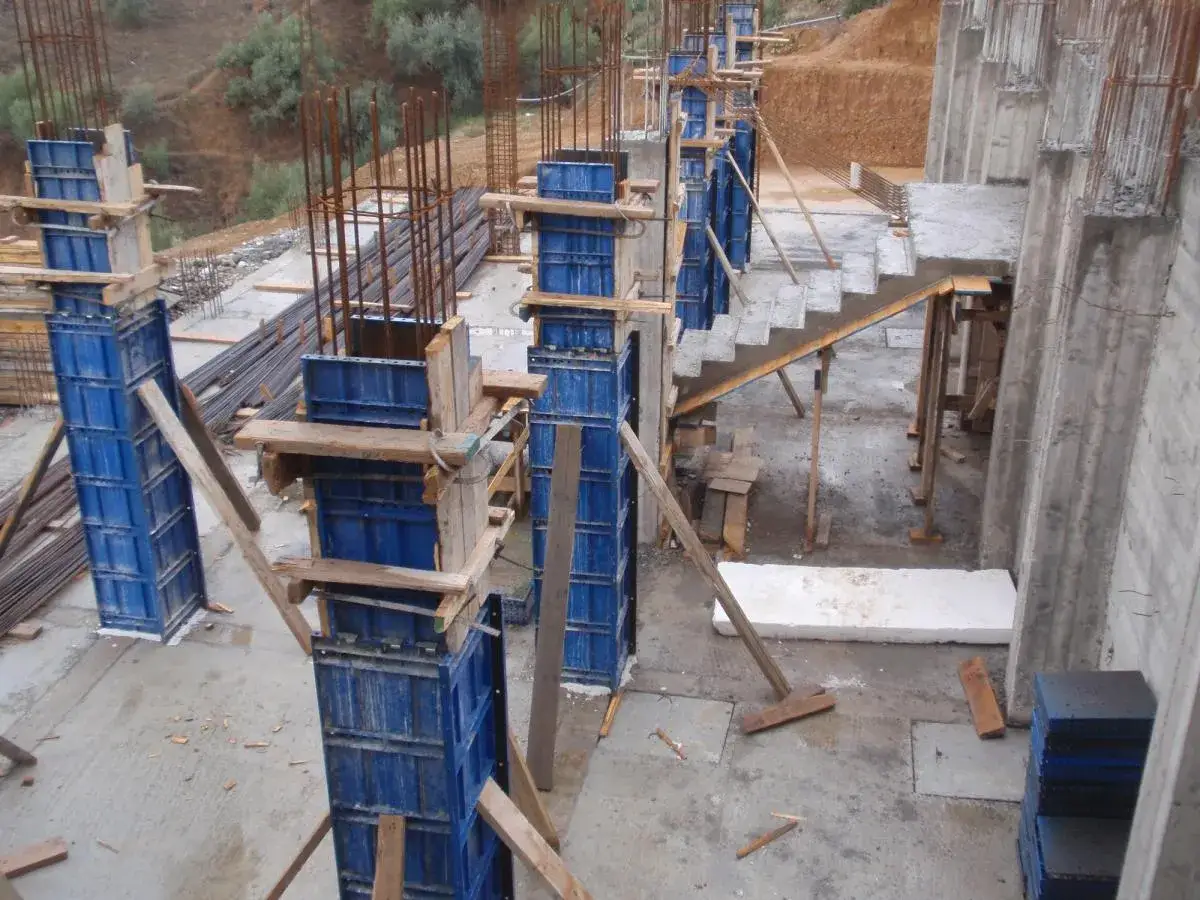 Estructura de hormigón en construcción con pilares de espadines encofrado, barras de acero y escaleras.