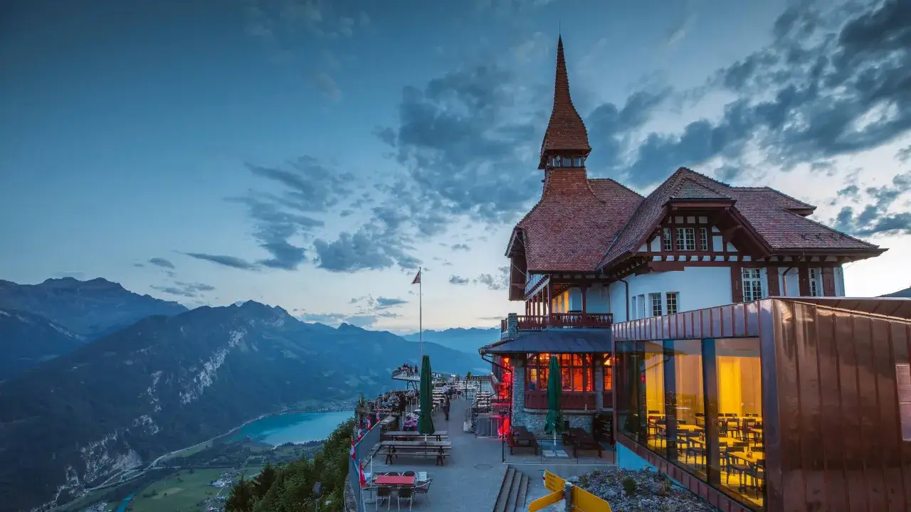 The Harder Kulm viewpoint offers a stunning panorama of mountains and a turquoise lake, with a charming Swiss chalet-style building.