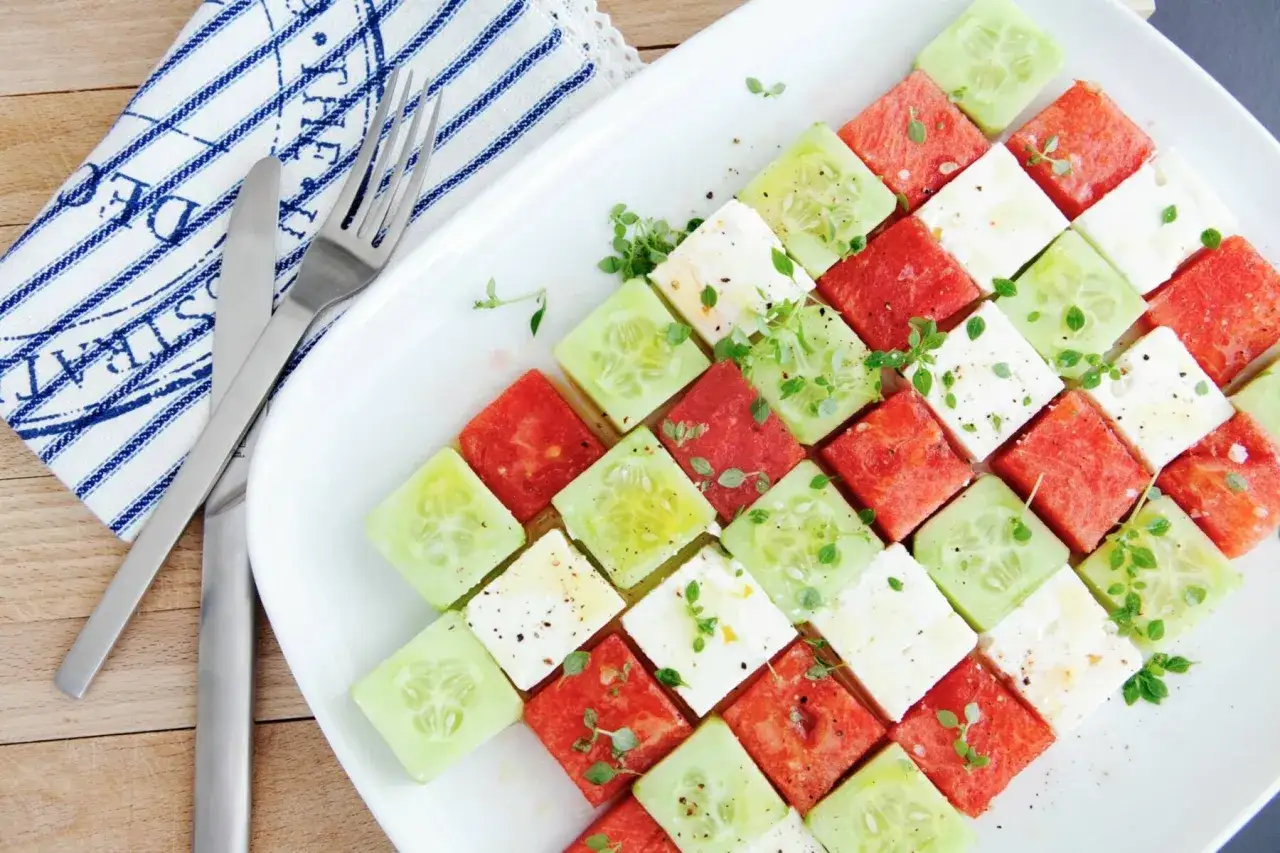 Erfrischender Melonen Feta Salat, kunstvoll arrangiert in Würfeln mit Gurke und frischen Kräutern.