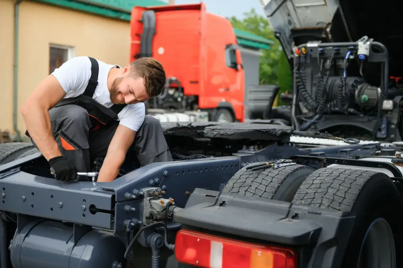 Mechanik naprawia ciężar&oacute;wkę, sprawdzając uszkodzony wahacz. Objawy mogą być r&oacute;żne, od nier&oacute;wnego zużycia opon po problemy z kierowaniem.