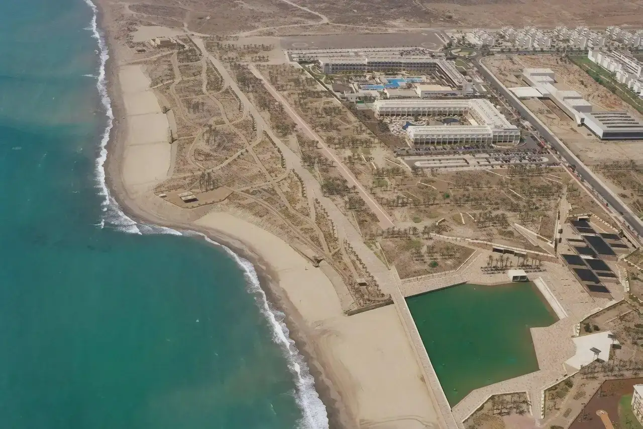 Vista aérea del paseo marítimo de Retamar con resorts, piscinas y la playa.