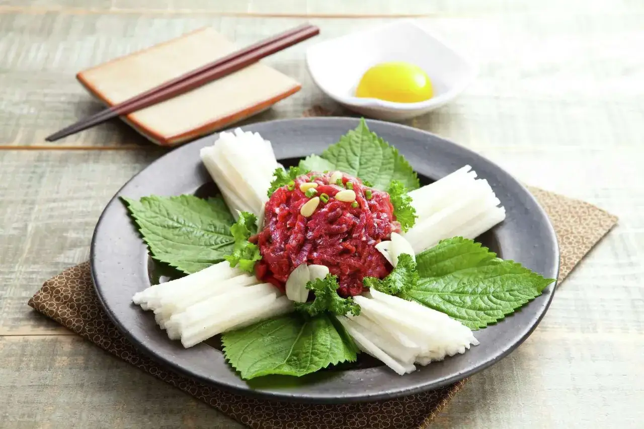 En vacker koreansk råbiff, serverad med krispiga grönsaker, nötter och en äggula. En delikatess att njuta av.