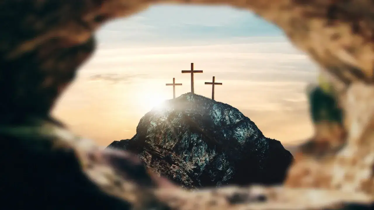 Drei Kreuze auf einem Felsen im Sonnenuntergang. Die Jesus Christus Bedeutung wird durch dieses Bild symbolisiert: Opfer, Erlösung und Hoffnung.