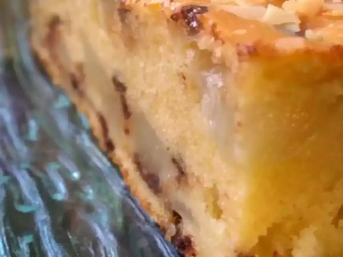 Tranche d'un délicieux gâteau poires amandes, parsemé de quelques éclats d'amandes sur le dessus.