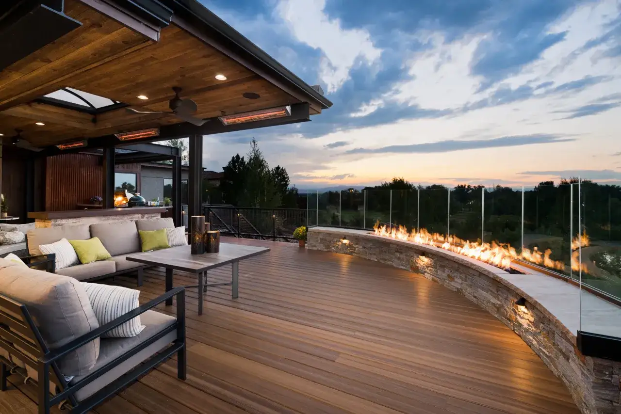 Une magnifique terrasse en L avec un foyer incurv&eacute;, des si&egrave;ges confortables et une vue imprenable au cr&eacute;puscule.