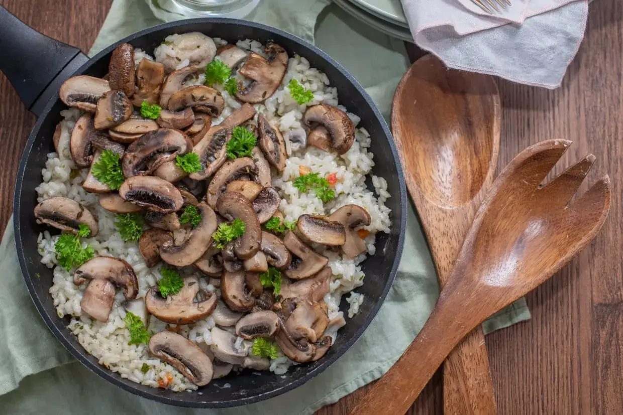 Délicieuse recette champignon de Paris avec riz crémeux, garnie de persil frais. Un plat réconfortant prêt à être dégusté.