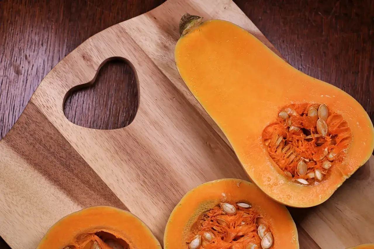 Hokkaido K&uuml;rbis und Butternussk&uuml;rbis nebeneinander auf einem Holztisch