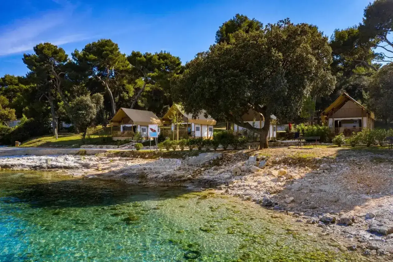 Namioty kempingowe na plaży w Arena Stoja campsite, z widokiem na krystalicznie czystą wodę i skaliste wybrzeże.