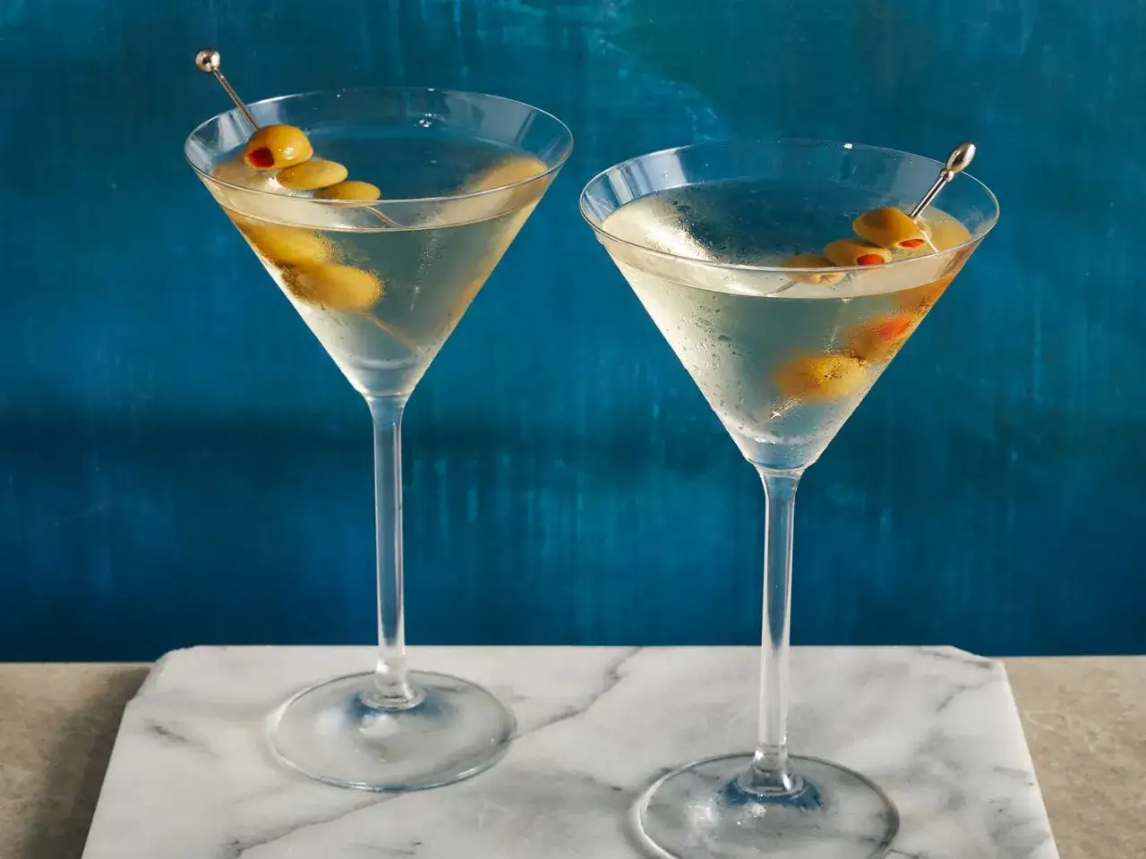 Dwa kieliszki z drinkami: Dirty Martini czy klasyczne Dry Martini? Oba z oliwkami, gotowe do degustacji.
