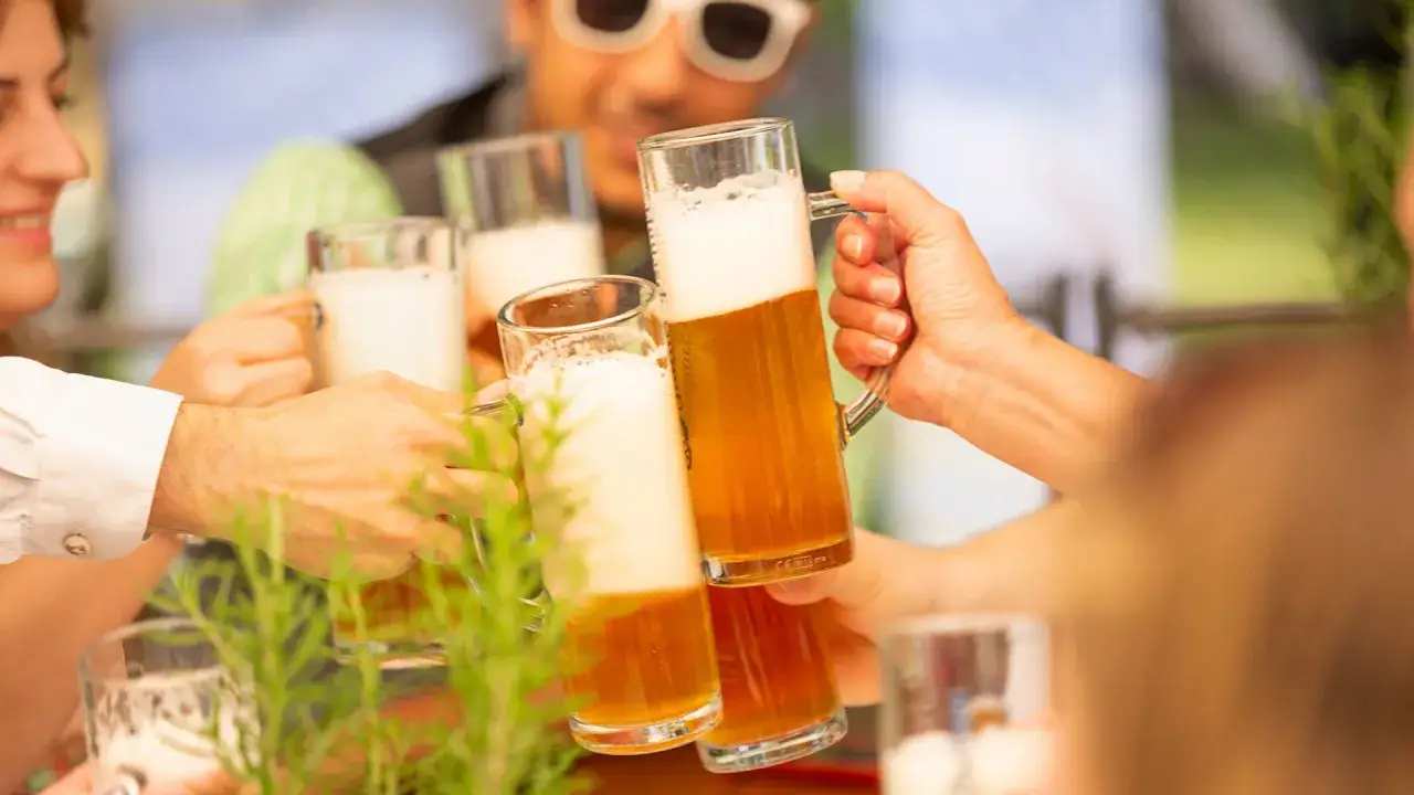 Freunde stoßen mit Bier an. Der goldene Gerstensaft mit cremigem Schaum verspricht einen köstlichen Bier Geschmack.