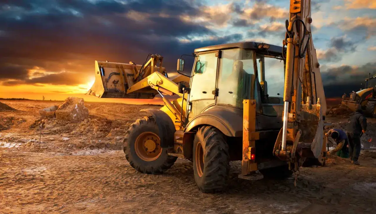 Excavadora amarilla en obra al atardecer, lista para continuar los proyectos de construcción.