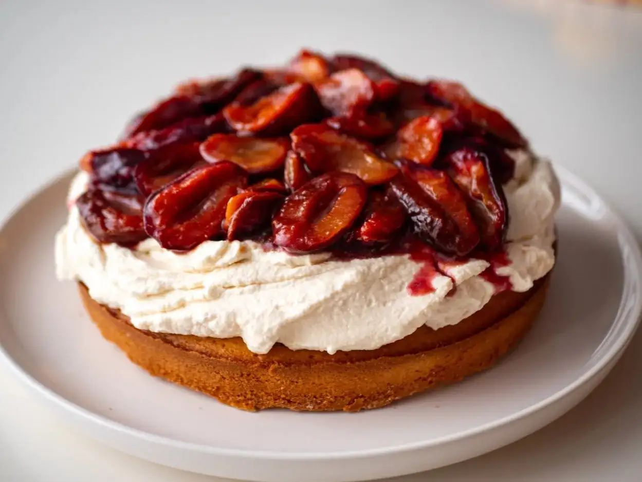 Gâteau moelleux garni d'une généreuse crème fouettée et de prunes caramélisées, une délicieuse composition de ricotta.