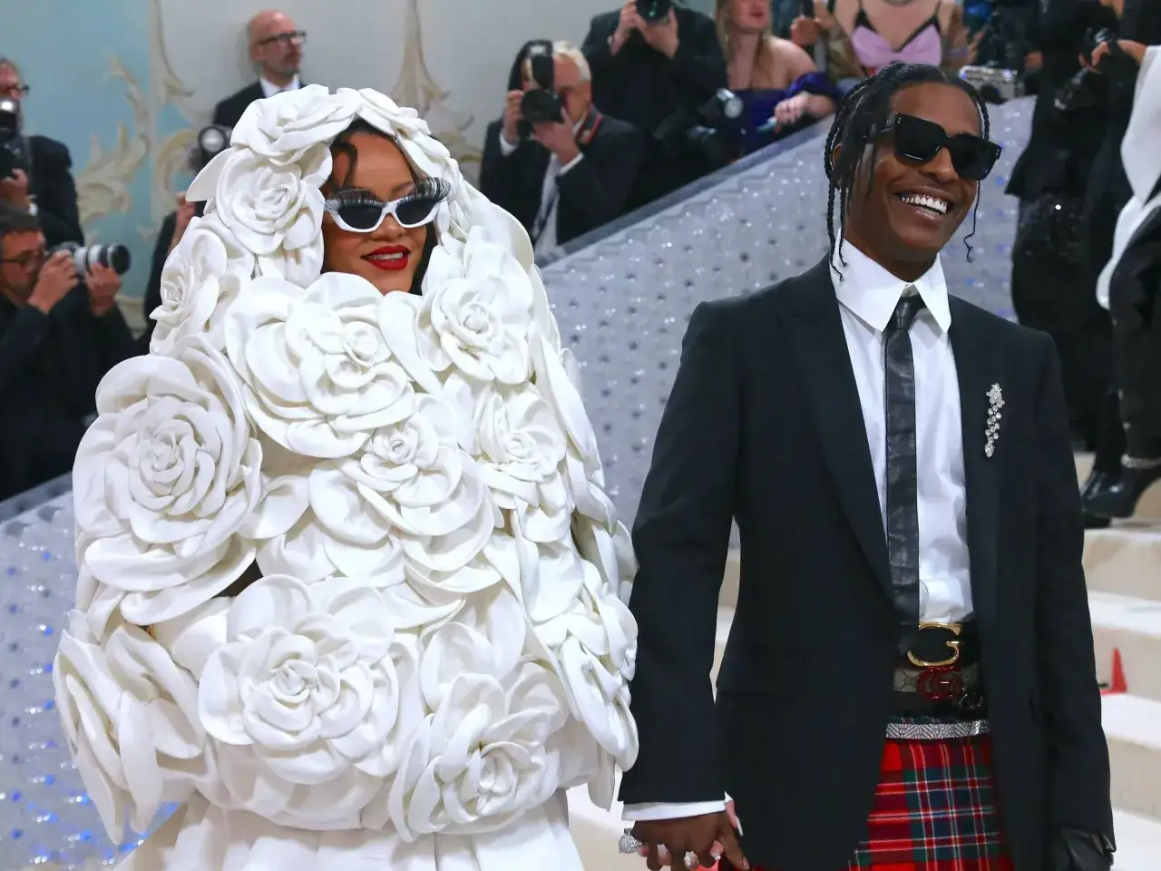 Rihanna w białej, kwiecistej kreacji i jej mąż A$AP Rocky w garniturze i szkockiej spódnicy.
