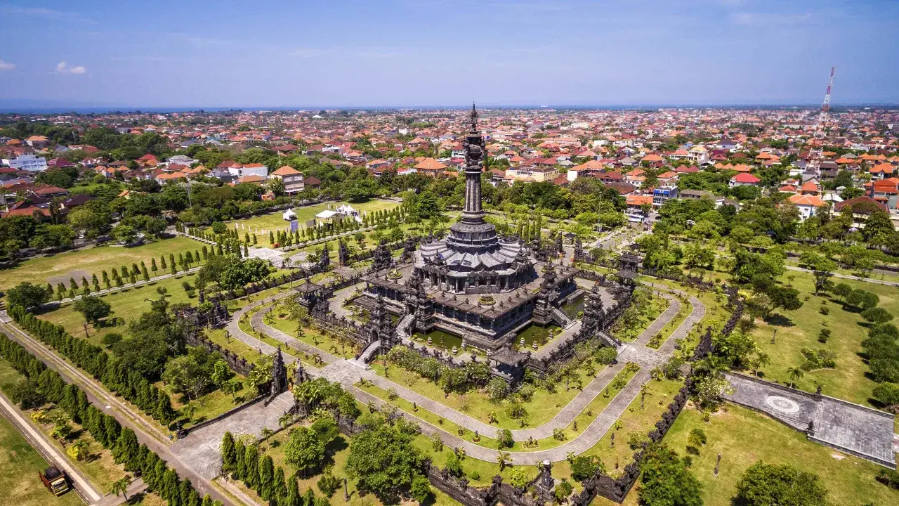 Widok z lotu ptaka na Bali. Monumentalna świątynia otoczona zielenią i miastem z czerwonymi dachami. Zastanawiasz się, ile się leci na Bali?