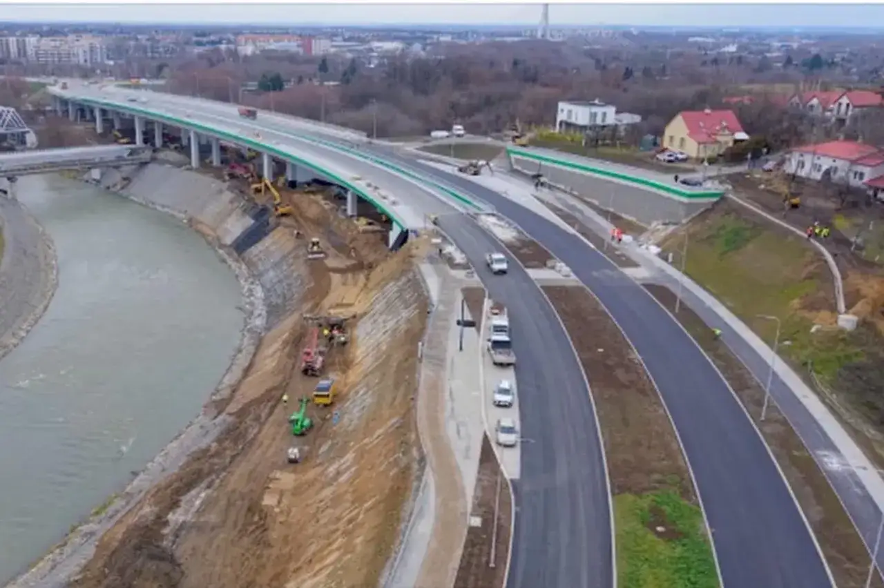 Budowa wisłokostrady w Rzeszowie. Maszyny budowlane pracują nad umocnieniem skarpy nad rzeką, a nowa droga jest już częściowo przejezdna.
