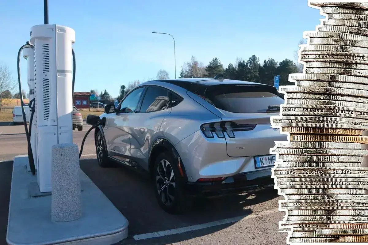 Silver elbil laddas vid en laddstation. En stapel mynt till h&ouml;ger antyder kostnaden f&ouml;r att k&ouml;ra en soc elbil.