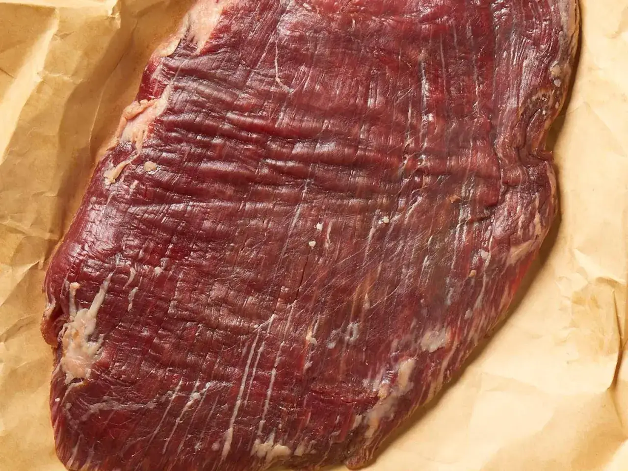 Rohes Flanksteak auf Backpapier. Für zartes Fleisch ist es wichtig, das steak richtig schneiden.