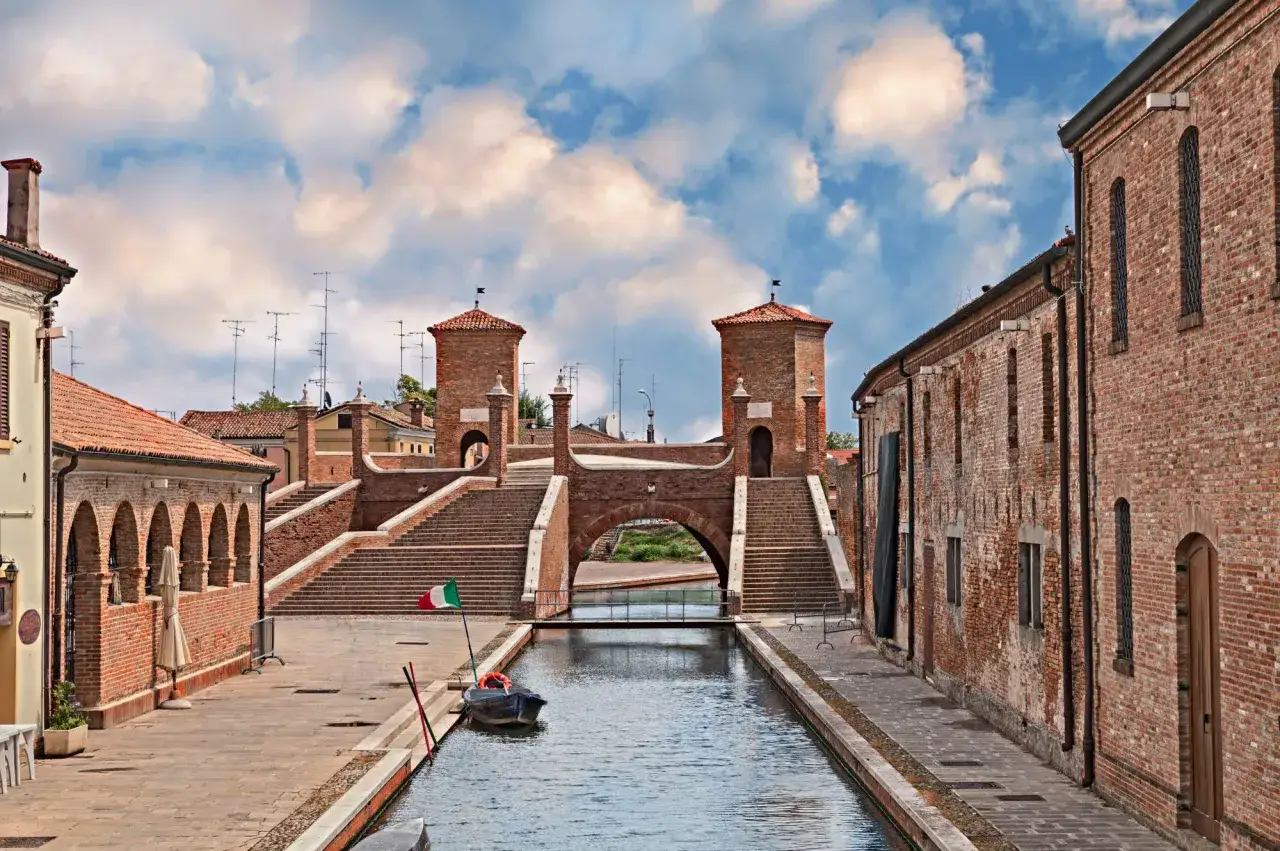 Il ponte del diavolo, con le sue torri in mattoni e le ampie scalinate, domina un canale tranquillo.