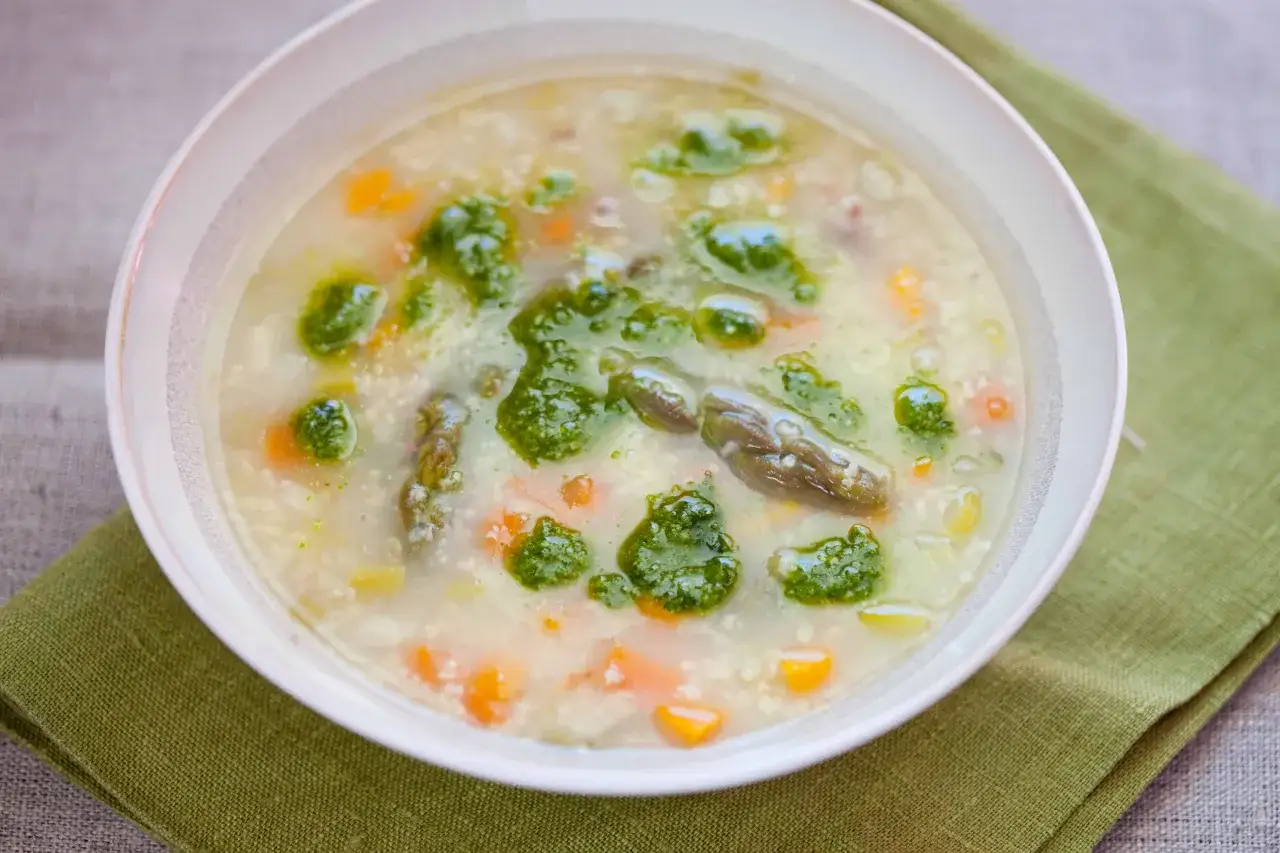 Zupa z kaszą, szparagami i marchewką, ozdobiona zielonym pesto. Idealna ilość kaszy do zupy, by była sycąca.