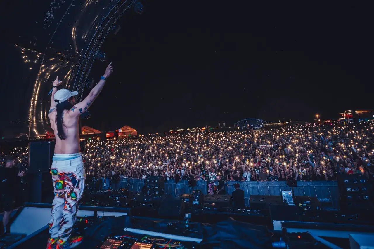 DJ na scenie Sunrise Festival 2026, tłum z telefonami w górze tworzy morze świateł.