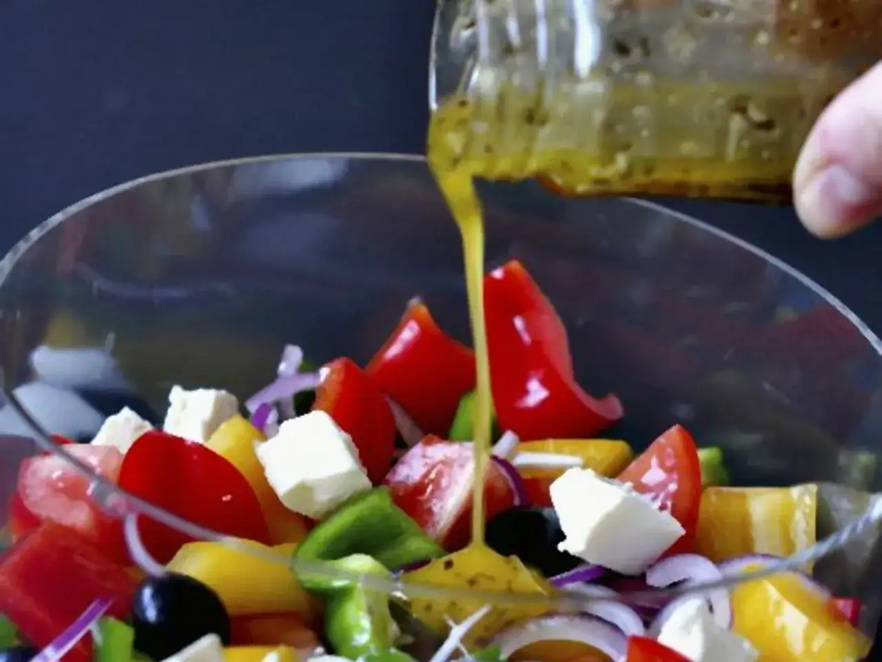 Frischer griechischer Salat mit Tomaten, Paprika, Feta und Oliven wird mit einem original griechischer salat dressing übergossen.