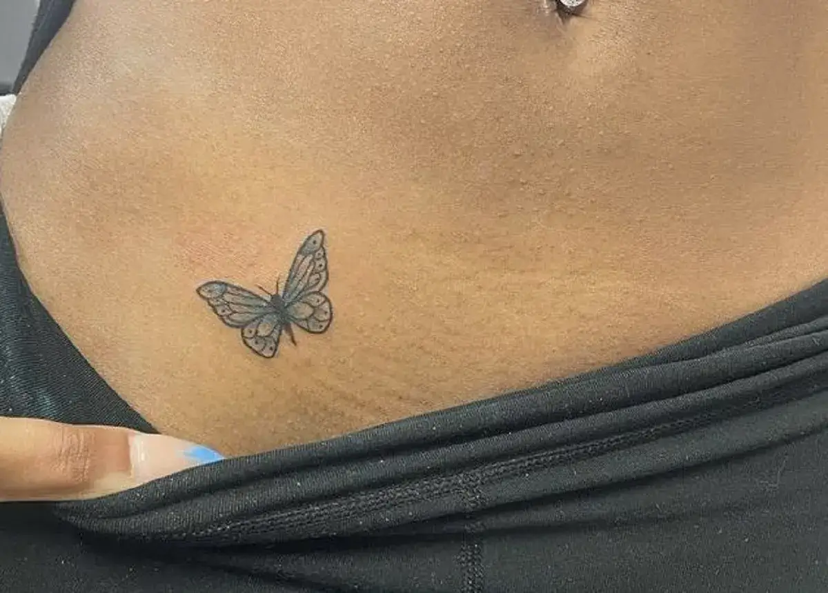 Delikatny tatuaż motyla na skórze, tuż nad linią bielizny.
