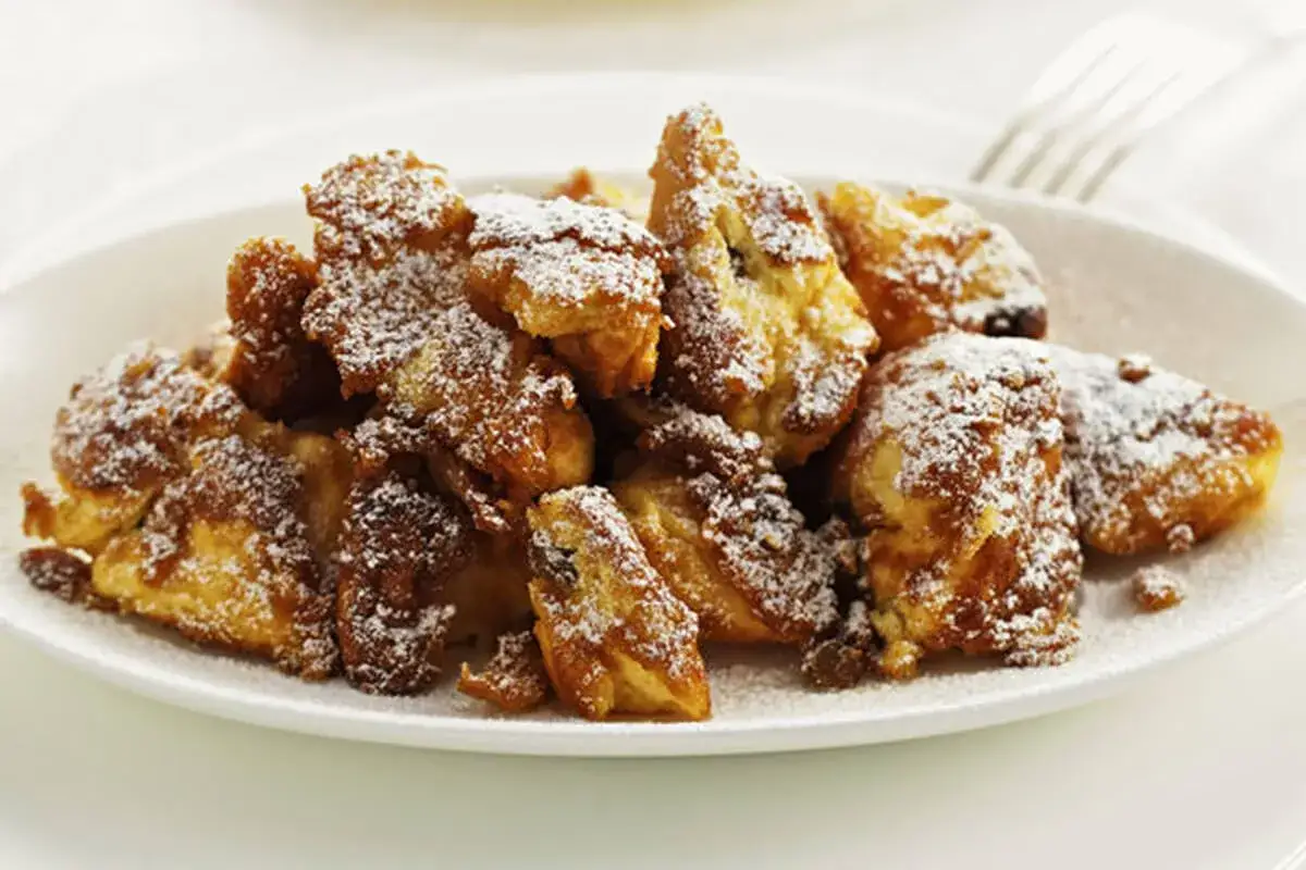 Ein Teller mit fluffigem Kaiserschmarrn, bestäubt mit Puderzucker, wie man ihn in Wien liebt.