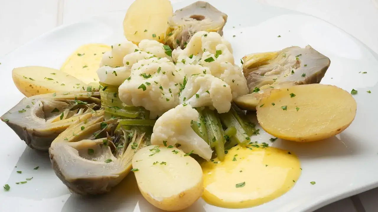 Un panache de verduras con coliflor, alcachofas, patatas y salsa holandesa, todo espolvoreado con perejil fresco.