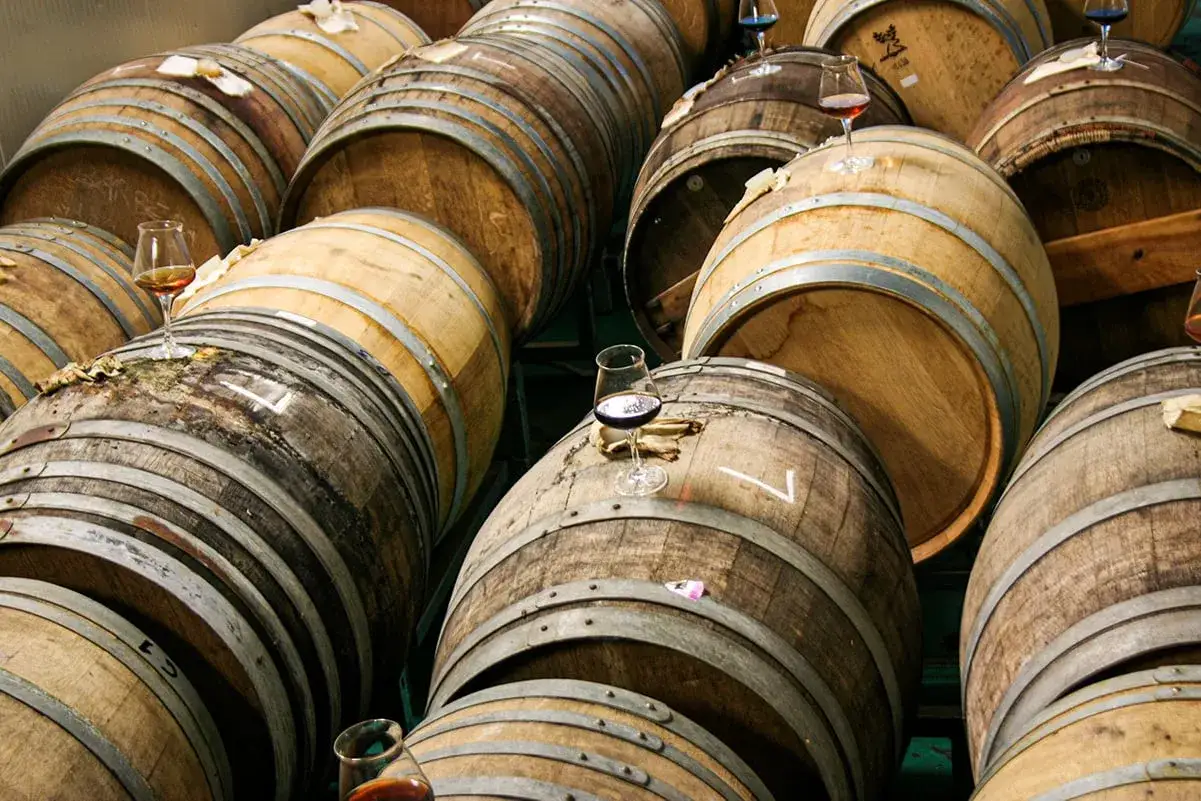 Botti di legno impilate, alcune con bicchieri di birra in attesa di essere degustate.
