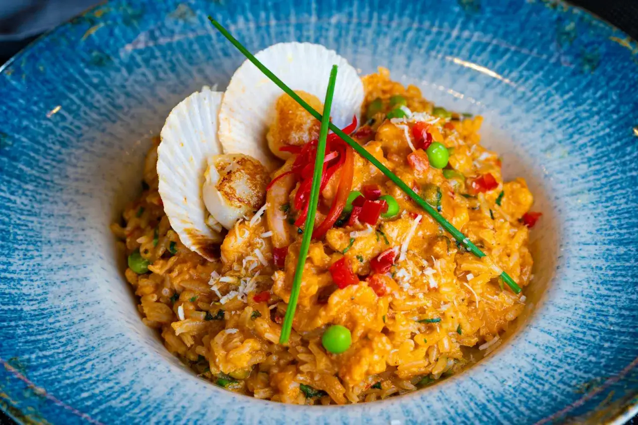 Un délicieux risotto aux fruits de mer, garni de noix de Saint-Jacques, crevettes, petits pois et poivrons rouges. Une recette risotto parfaite pour un repas savoureux.