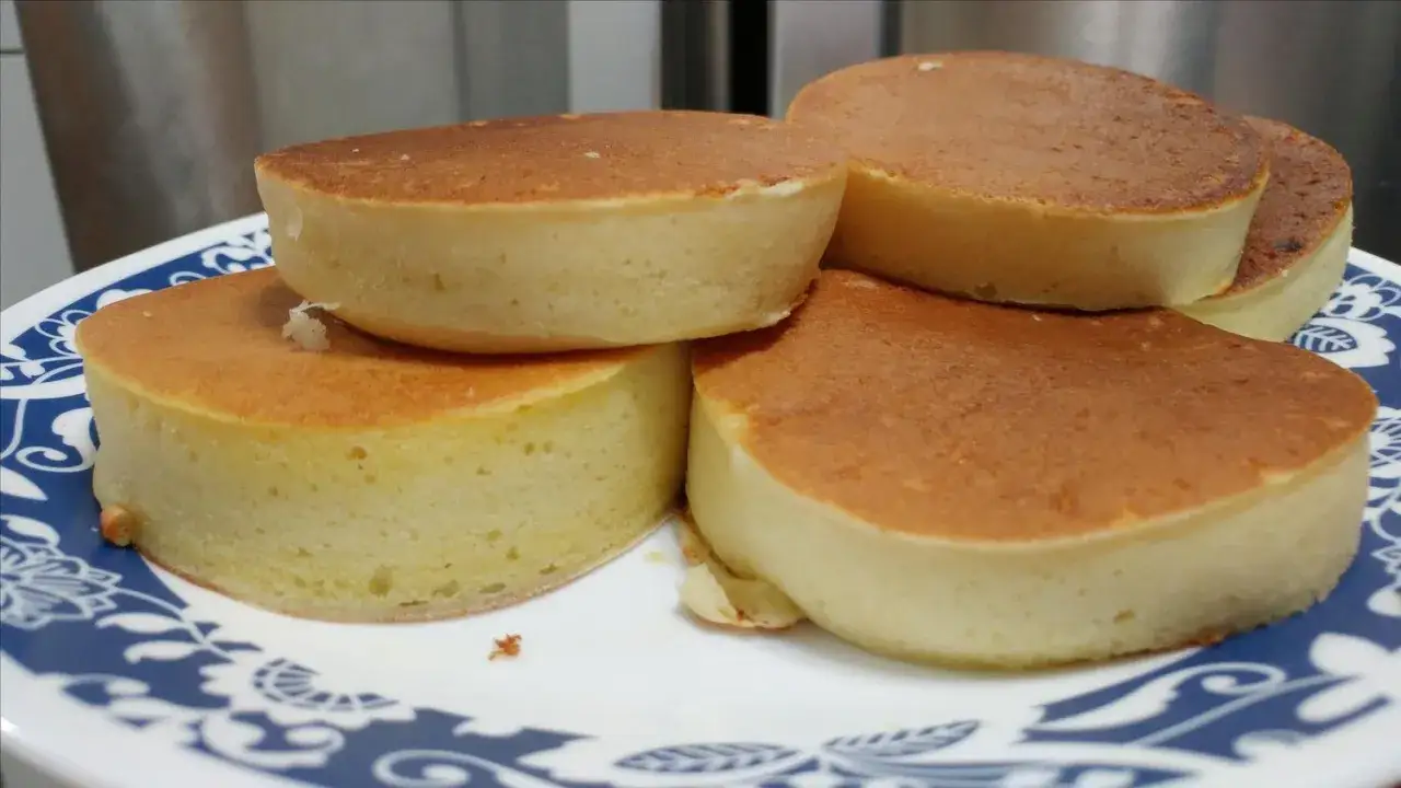 Fluffiga japanska pannkakor staplade på en blåvit tallrik. De ser otroligt mjuka och läckra ut!