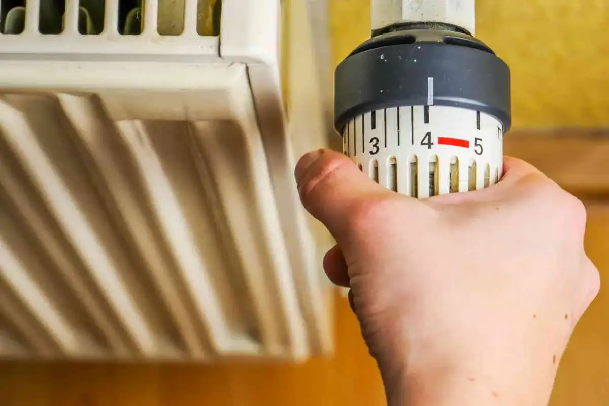 Mano che regola la manopola del termosifone, impostando la temperatura. Scopri come funziona per un comfort ottimale.