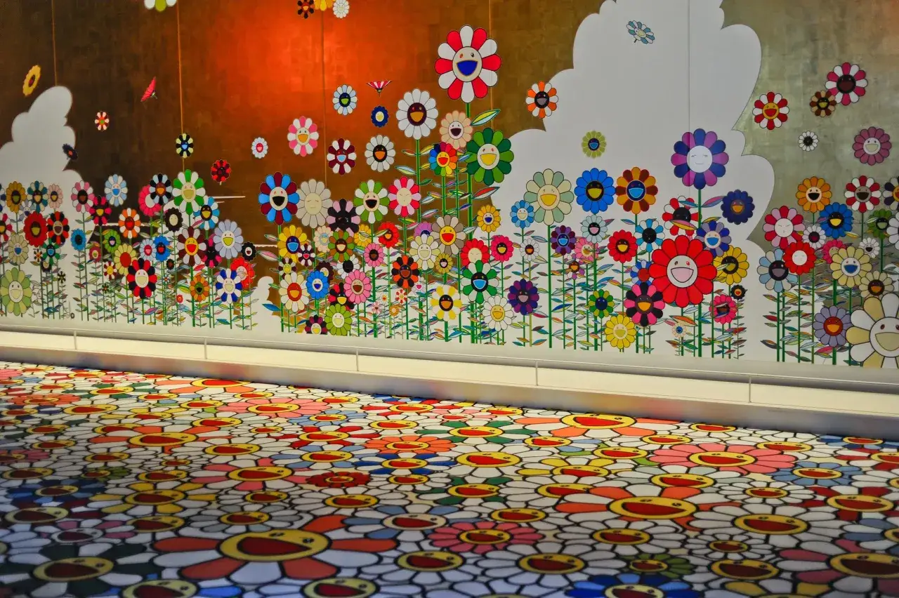 Un mur et un sol recouverts de fleurs souriantes colorées, signature de l'artiste Murakami.