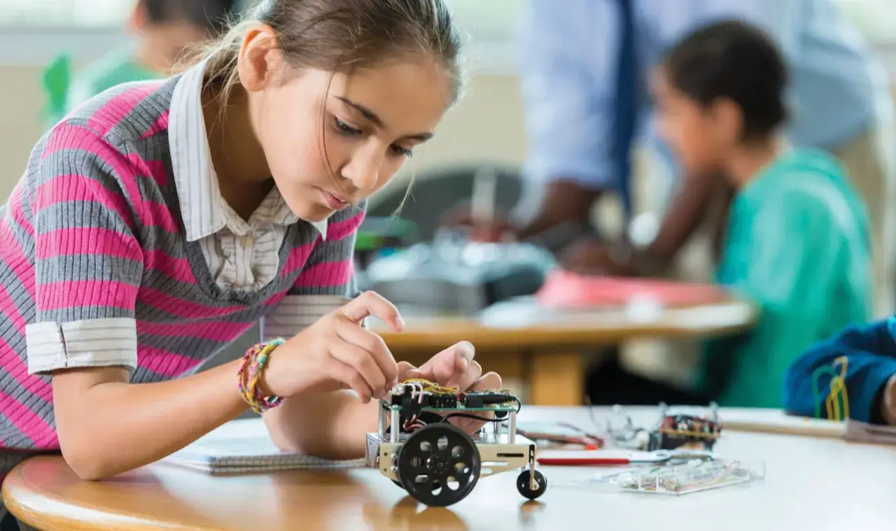 Ni&ntilde;a concentrada armando un robot, aplicando la metodolog&iacute;a STEM en un aula.