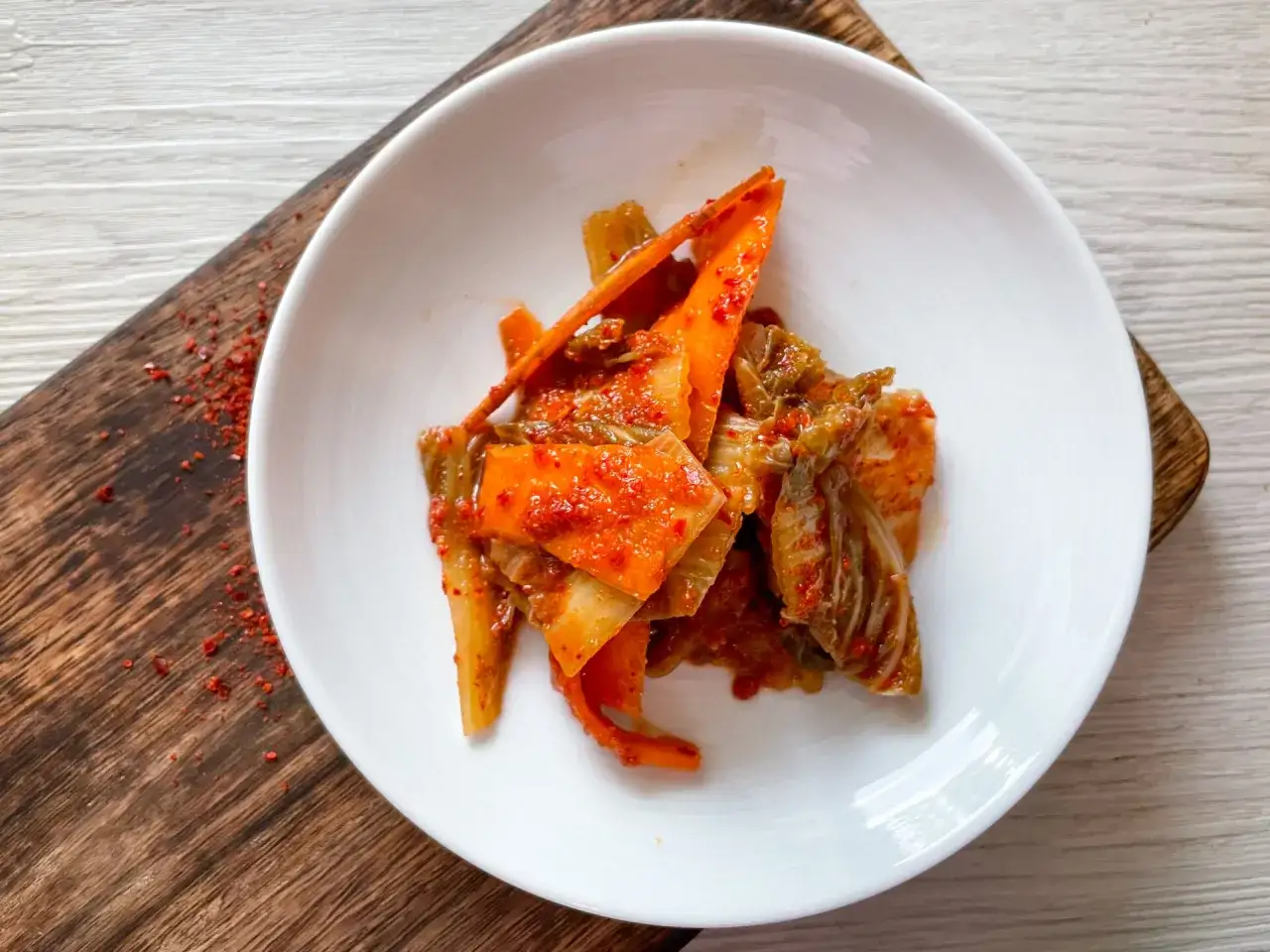 Frisch zubereitetes Kimchi, das beste Kimchi Rezept, serviert auf einem weißen Teller. Würzig und rot, bereit zum Genießen.
