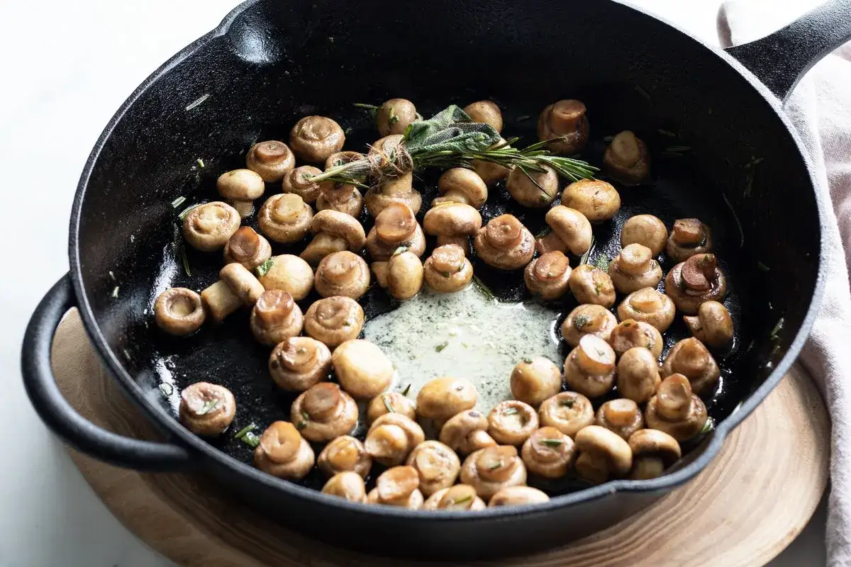 Champignons à la crème dans une poêle en fonte, avec des herbes fraîches. Un délice simple et savoureux.