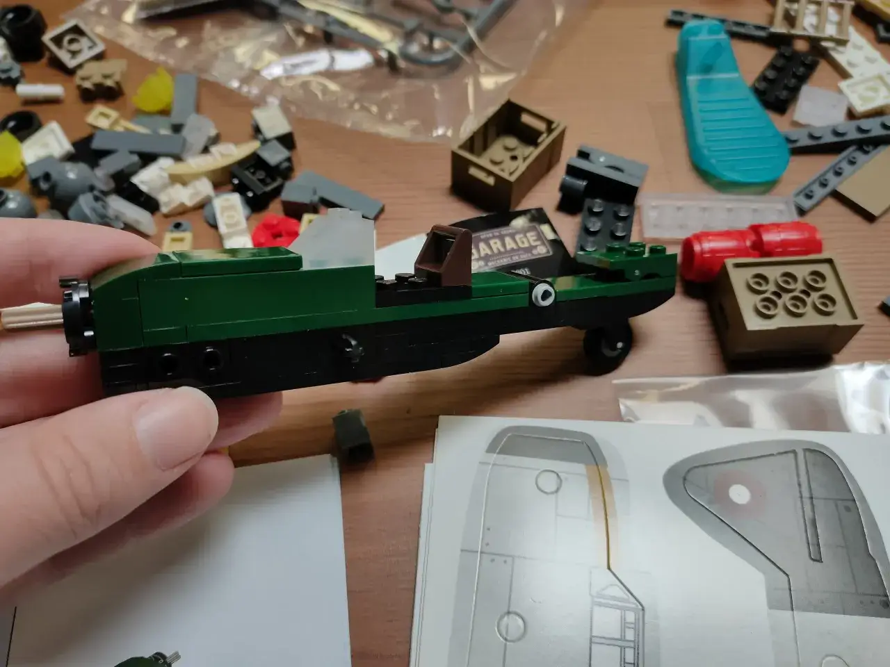 Bunte Bausteine liegen verstreut, während eine Hand ein grünes Modellauto hält. Die **cada bauanleitungen** liegen daneben.
