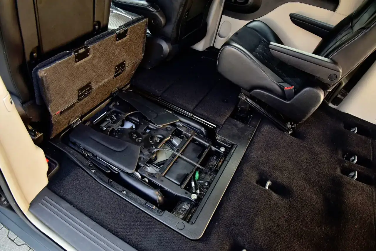 Wnętrze kombi auta z podniesioną klapą schowka pod siedzeniem. Widoczne mechanizmy i czarne, skórzane fotele.