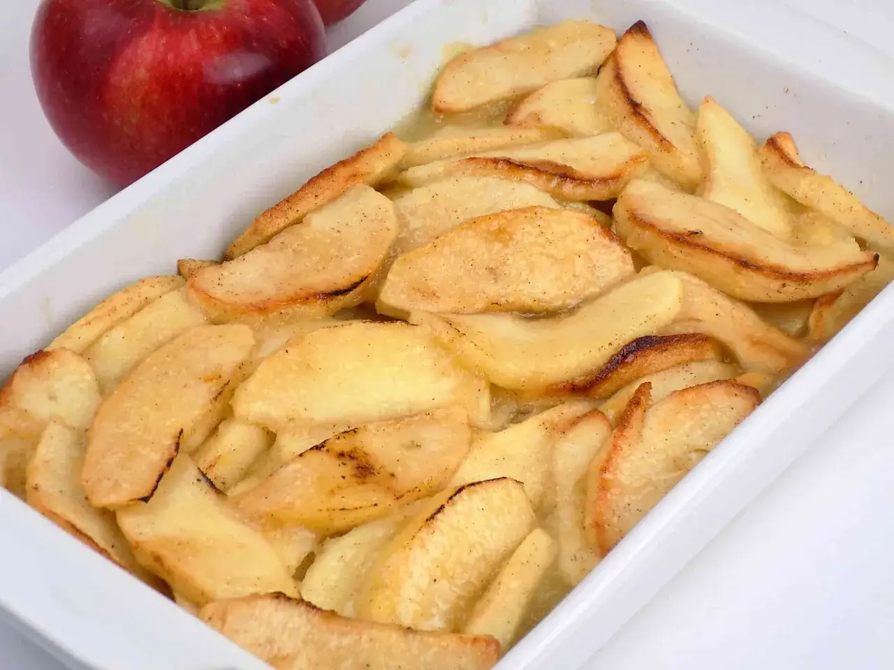 Pieczone jabłka dietetyczne w naczyniu, lekko przypieczone na brzegach, z cynamonem. Idealne na zdrowy deser.