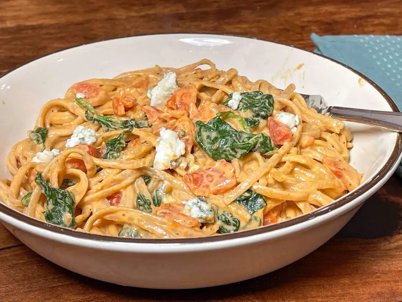 Pasta mit cremiger spinat gorgonzola sauce, Tomatenstücken und zerbröseltem Gorgonzola.