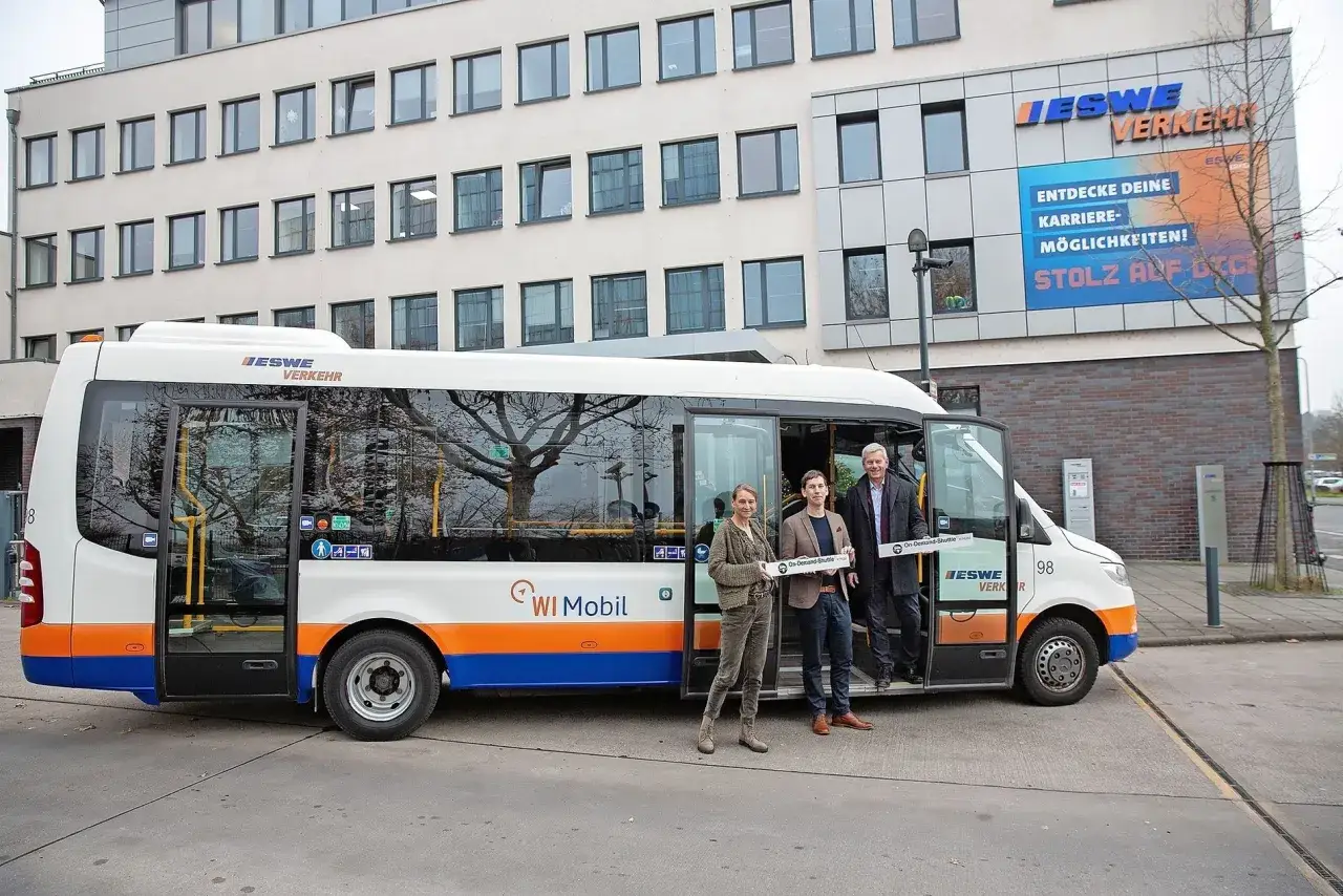Drei Personen stehen vor einem ESWE-Verkehrsbus. Sie halten Schilder mit der Aufschrift 