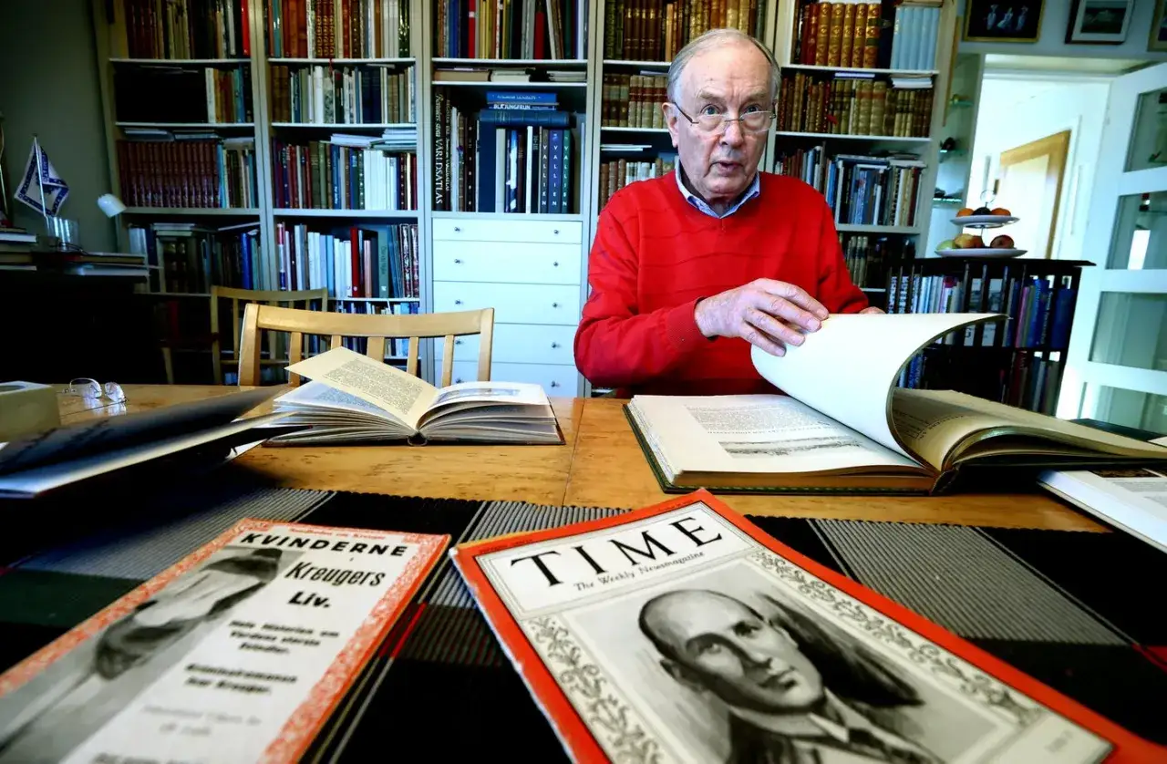 Äldre man i röd tröja bläddrar i bok. På bordet ligger böcker och tidningar, bland annat en om Kvinnorna Kreugers liv.